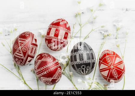 Red and black handmade Easter Pysanka eggs. Ukrainian pysanky decorated with wax-resist dyeing technique. White wooden background Stock Photo