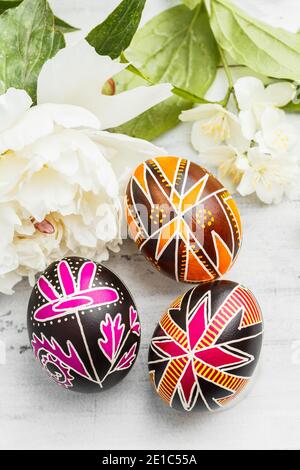 Three handmade Easter eggs decorated with wax-resist dyeing technique. Ukrainian pysanky on the table. Vertical composition Stock Photo