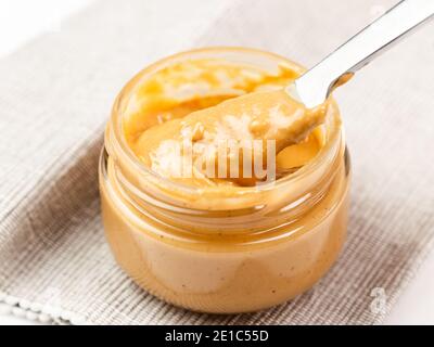 Crunchy peanut butter in a glass jar, close up Stock Photo
