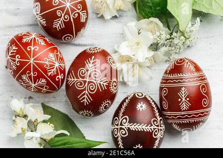 Red and black handmade Easter Pysanka eggs. Ukrainian pysanky decorated with wax-resist dyeing technique. White wooden background Stock Photo