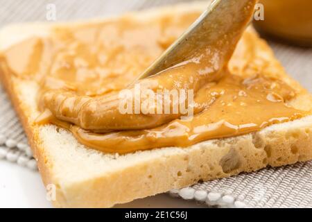 Crunchy peanut butter spreading on a toast, close up Stock Photo