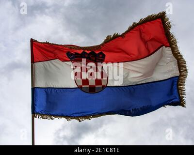 Croatian flag waving in the wind. A cloudy, windy day. Jagged flag. Stock Photo