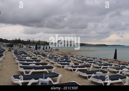 Coming storm threw all the people into the hotel. beautiful beach in Cyprus in bad weather. Ayia napa beach with many deck chairs on sand beach. Deser Stock Photo