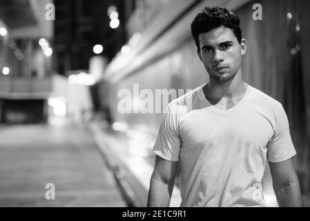 Young handsome Hispanic man exploring the city streets at night Stock Photo