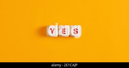 The word yes on wooden cubes with alarm clock. Business or positive personal decision making concept. Stock Photo