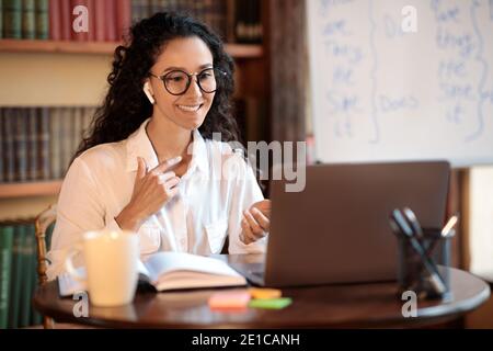 Woman sitting at desk, explaining lesson to students Stock Photo