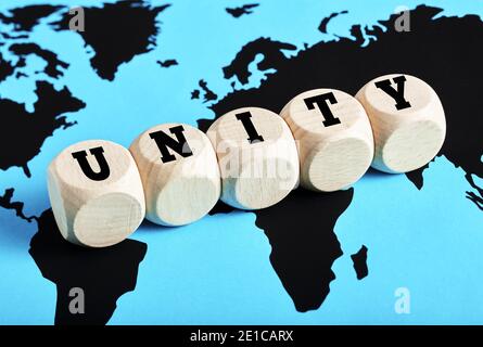 The word unity written on wooden cubes on world map background. International teamwork, alliance, collaboration or communication around the globe conc Stock Photo