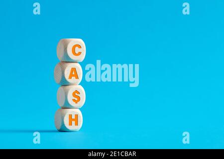 The word cash on tiered wooden cubes on blue background. Cash increase or growth concept. Stock Photo