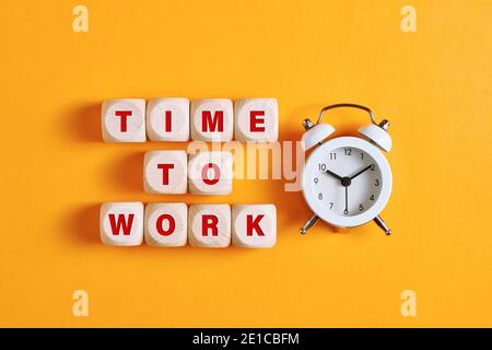 The word time to work on wooden cubes with alarm clock. Business, career or working hard concept. Stock Photo