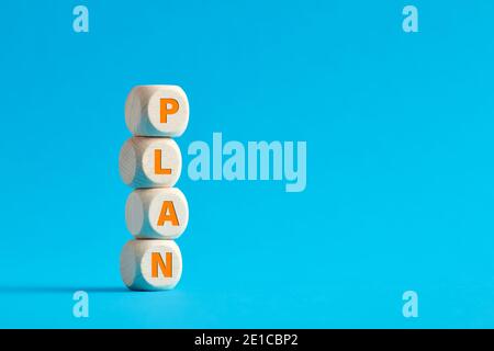 The word plan on tiered wooden cubes on blue background. Stock Photo