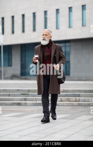 Successful aged businessman going from business meeting, drinking coffee Stock Photo
