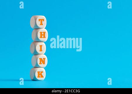 The word think on tiered wooden cubes on blue background. Thinking and creativity concept. Stock Photo