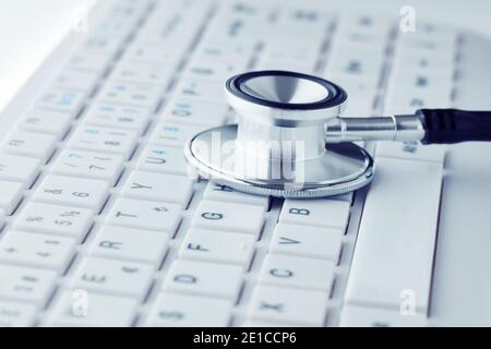 Stethoscope on white computer keyboard. Computer repair service or online health care concept Stock Photo