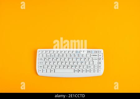 White computer keyboard on yellow background with copy space. Overhead view. Stock Photo