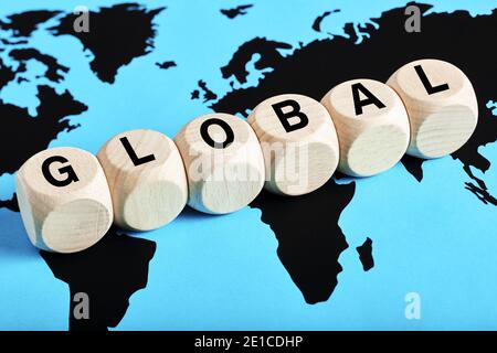 The word global written on wooden cubes on world map background. Globalization concept. Stock Photo