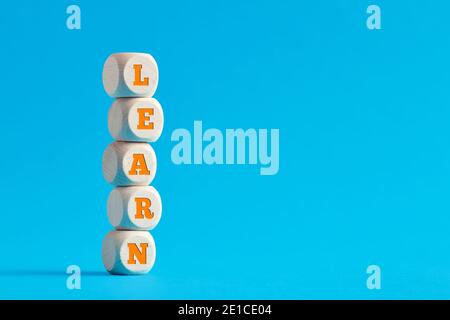 The word learn on tiered wooden cubes on blue background. Stock Photo