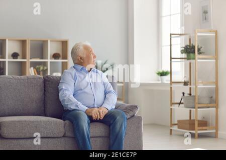 Senior man sitting on sofa, thinking about life and recollecting memories of days gone by Stock Photo