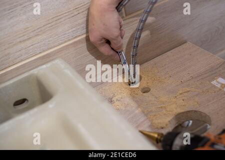 Installing a bathroom sink on a wooden countertop. Plumbing work. Stock Photo