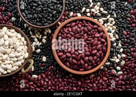 red kidney beans in brown ceramic bowl. wooden bowl copper bowl of beans. black bean, red kidney bean. navy bean, cannellini bean, white kidney bean. Stock Photo