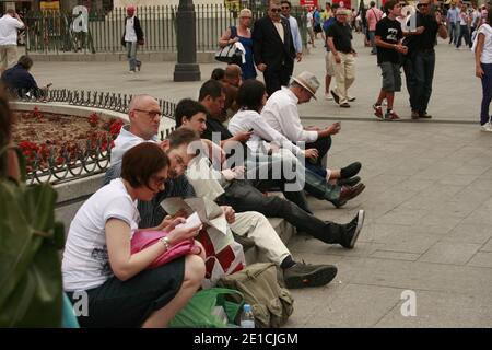 Tourists spend time sitting on a bench in Plaza Mayor in central Madrid Stock Photo