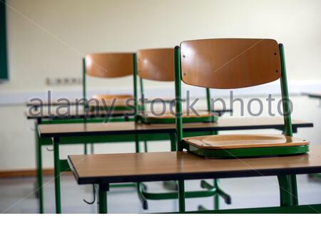 A set of chairs on school deasks in a deserted classroom as the Corona crisis continues. Stock Photo