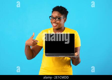 Happy Black Lady Showing Laptop Screen Standing Over Blue Background Stock Photo