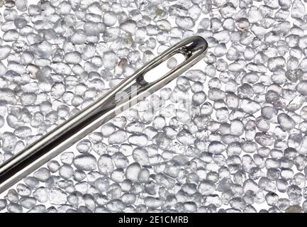 Sand in the eye of a needle magnified at 5x magnification photographed on a white background Stock Photo
