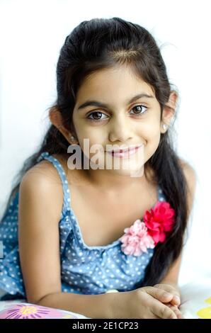 PORTRAIT OF A BEAUTIFUL AND FASHIONABLE, SMILING  INDIAN GIRL CHILD MODEL , IN A  SITTING POSTURE WITH HANDS JOINED.