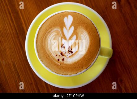 Cup of cappuccino coffee with latte art isolated on wooden table Stock Photo
