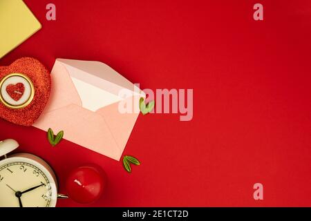 Valentine's day flat lay composition on red background, love letter envelop, candle in form of heart and decoration banner, copy space photo Stock Photo
