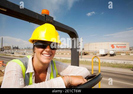 Ali Walker drives a large road rolling machine at the Syncrude Mildred Lake tar sands plant. The Alberta tar sands in Canada are the largest industria Stock Photo