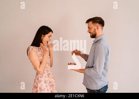 Young man with engagement ring making a proposal to his beloved girlfriend. The ring is in the eclairs Stock Photo