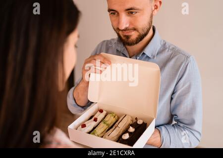 Young man with engagement ring making a proposal to his beloved girlfriend. The ring is in the eclairs Stock Photo