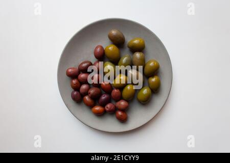 Green and purple olives on grey concrete plate isolated on white background from a high angle view Stock Photo