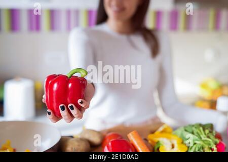 Close up of girl holding red paprika in her hands. Focus is on paprika. Stock Photo