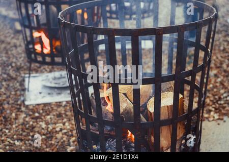 Close up fire baskets filled with burning wood and flames outdoor. Selective focus, copy space. Stock Photo