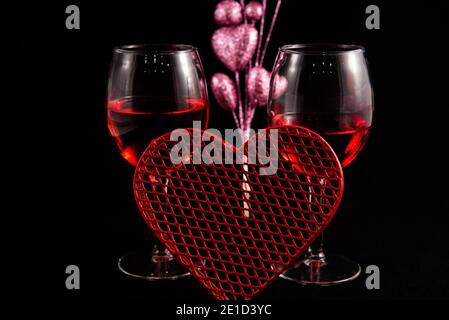 Two wine glasses with Valentines hearts against a black background. Stock Photo