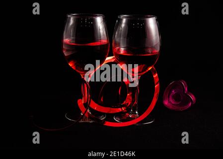 Two wine glasses with Valentines hearts against a black background. Stock Photo