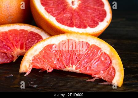 Red Grapefruit Sliced into Wedges: A pink grapefruit sliced in half and into smaller wedges Stock Photo