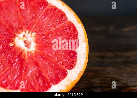 Red Grapefruit Sliced in Half: A halved pink grapefruit on a dark wood cutting board Stock Photo