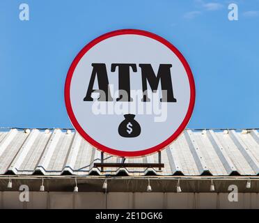 A Circle billboard with icon an ATM is installed on a roof. Board with sign of finance service and automated teller machine. Stock Photo