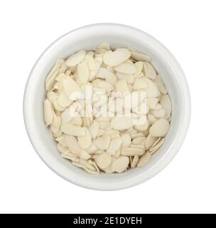 Pile of peeled flaked almonds in a bowl isolated on white. Blanched almonds flakes on white. Stock Photo