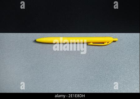Black sheet of paper and a yellow pen on a gray background. flat lay, top view, copy space Stock Photo
