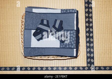 Yukata or house robes, folded in a basket on the tatami mat floor to await guests at a traditional Japanese ryokan or inn Stock Photo