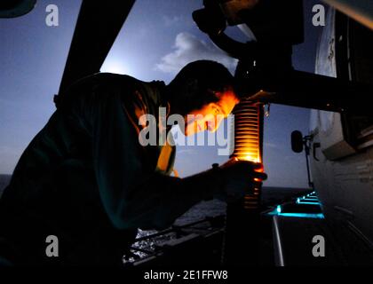 Naval Air Crewman 2nd Class Jordan Orr, assigned to Helicopter Sea Combat Squadron (HSC) 22, checks the mount for a GAL-21 machine gun on an MH-60S Sea Hawk helicopter on the flight deck of amphibious assault ship USS Kearsarge (LHD 3) in preparation for operation Odyssey Dawn missions. Joint Task Force Odyssey Dawn is the U.S. Africa Command task force established to provide operational and tactical command and control of U.S. military forces supporting the international response to the unrest in Libya and enforcement of United Nations Security Council Resolution (UNSCR) 1973. Mediterranean S Stock Photo