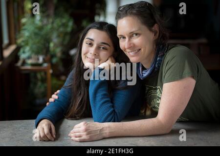 Mother with arm around pretty teen daughter smiling at camera Stock Photo