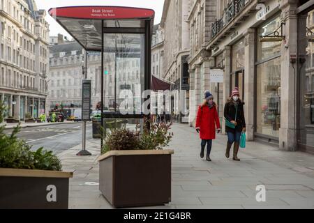 London, UK. 06th Jan, 2020. A couple wearing facemasks as a preventative measure against the spread of covid 19 walk along a semi- deserted Regent Street.England's third national lockdown legally comes into force. Credit: SOPA Images Limited/Alamy Live News Stock Photo