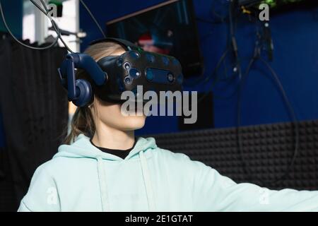 Teen girl using virtual reality headset in dark room of vr gaming club. Concept of virtual simulation, gaming, internet of things. Stock Photo