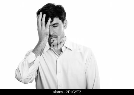 Studio shot of young Persian businessman looking tired while covering face Stock Photo