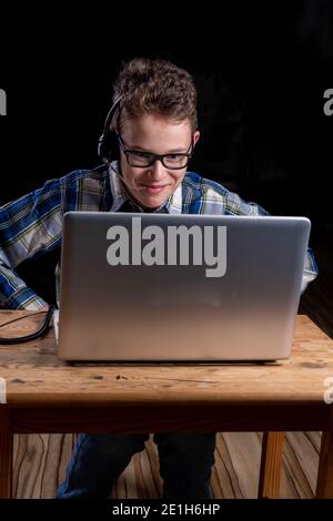Boy with shirt and glasses headset doing e learning on laptop Stock Photo
